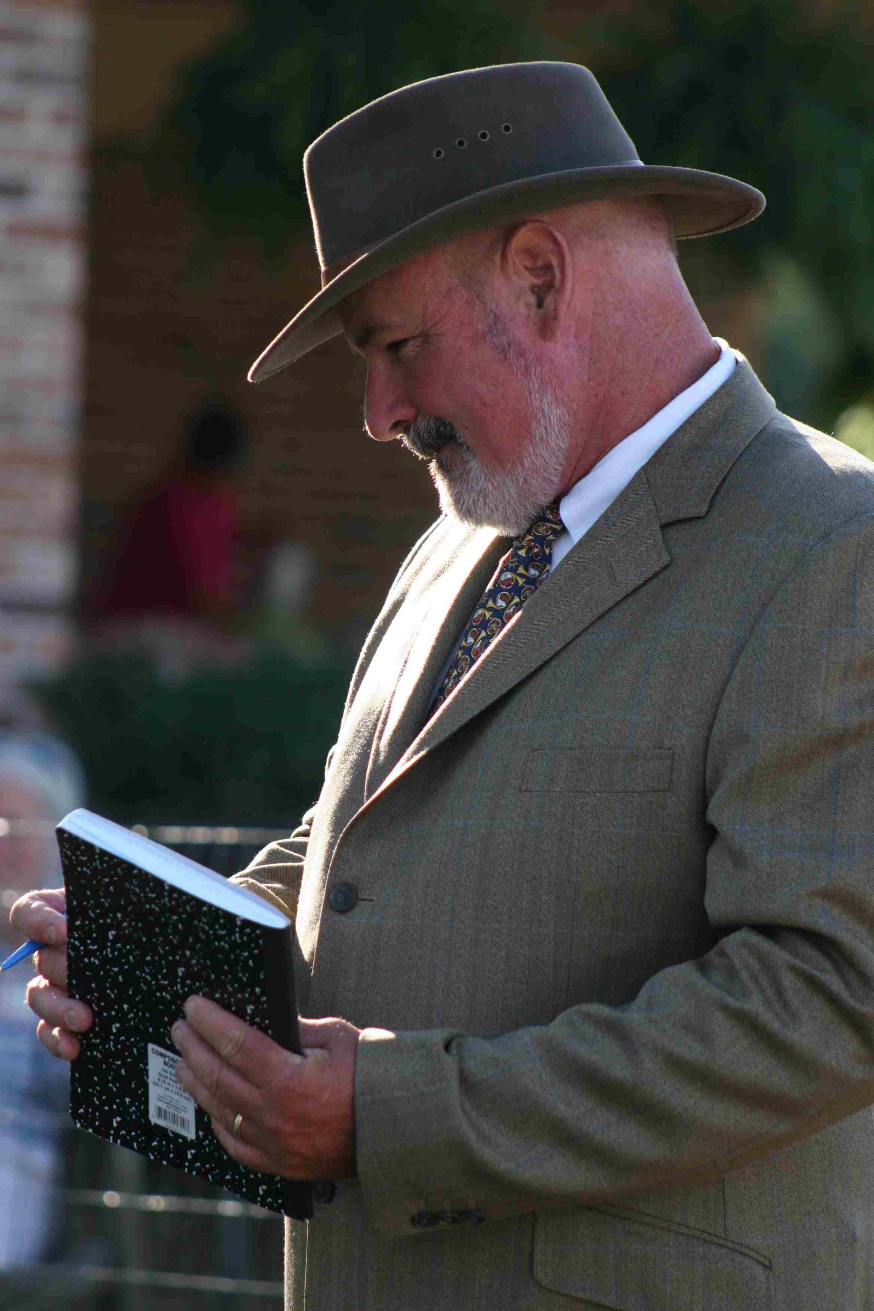 smiling man outdoors in suit coat with notebook