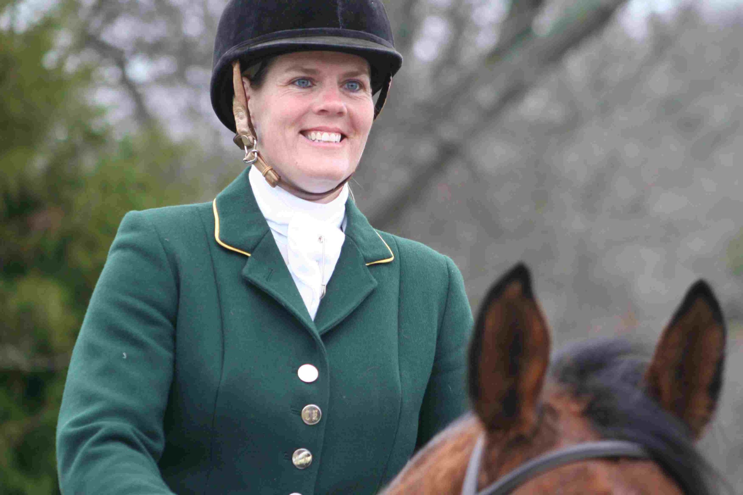 smiling woman in green hunt coat and helmet