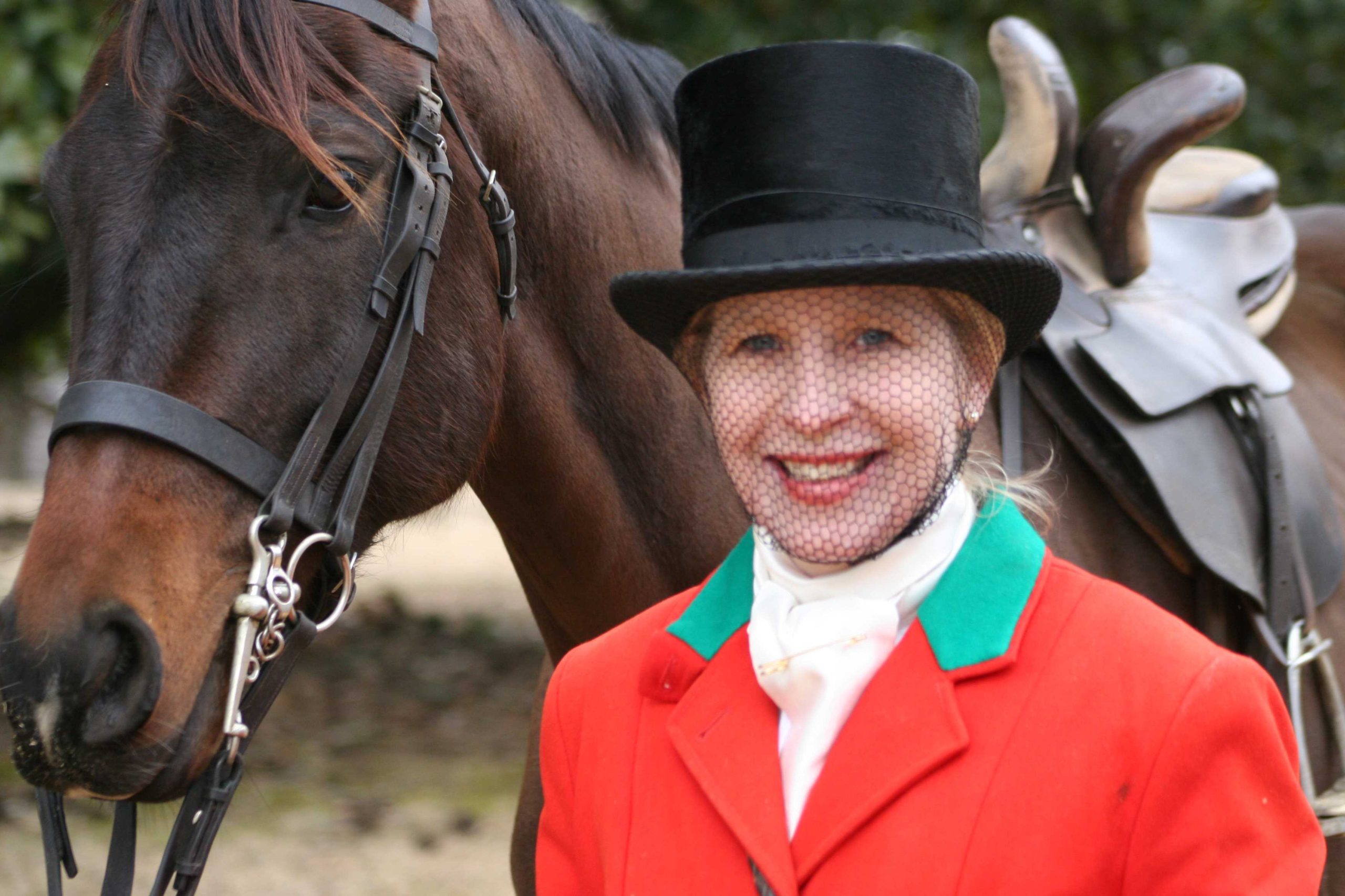 woman in red coat with top hat and veil, with horse in background