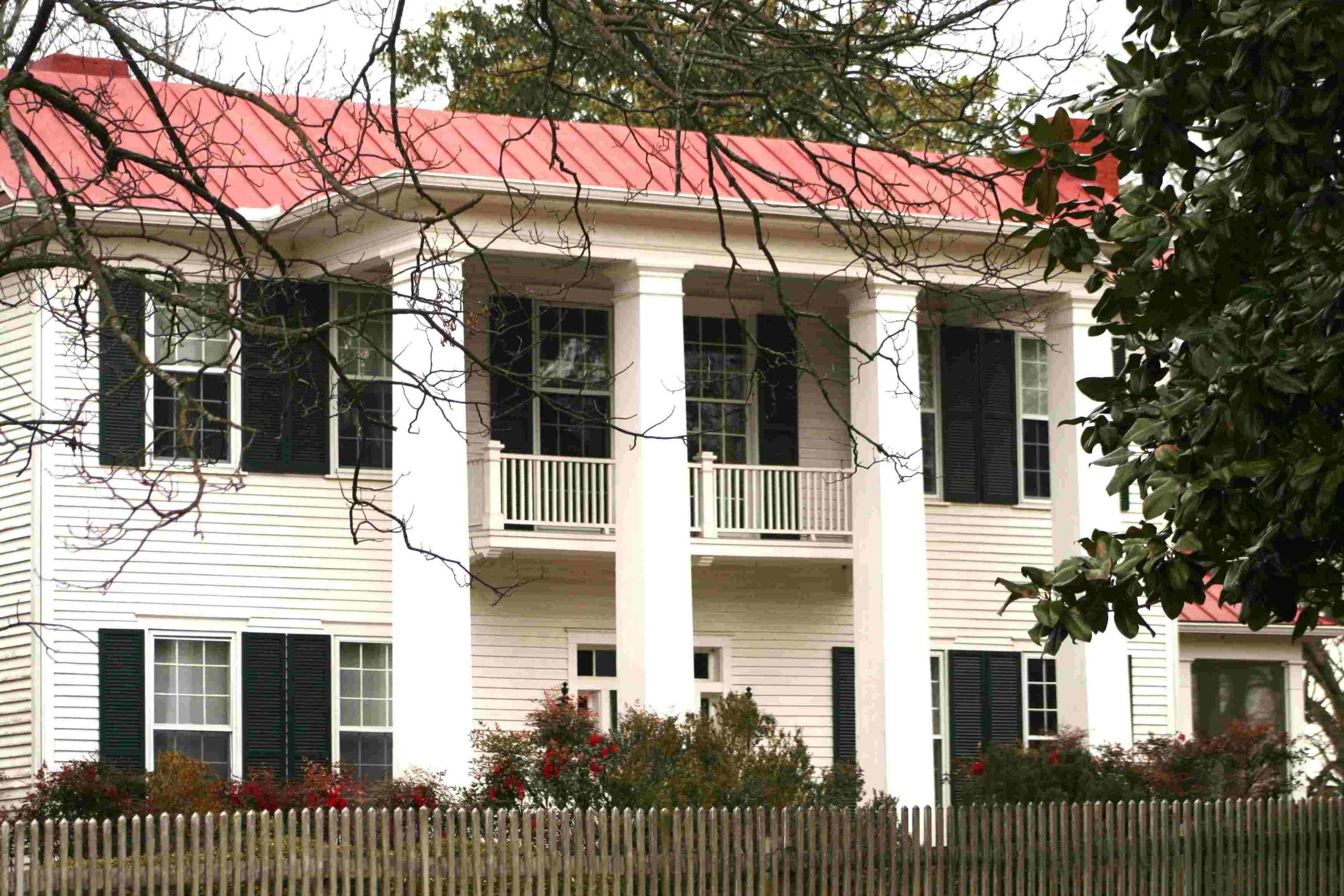 historic white home with porches and columns, red roof