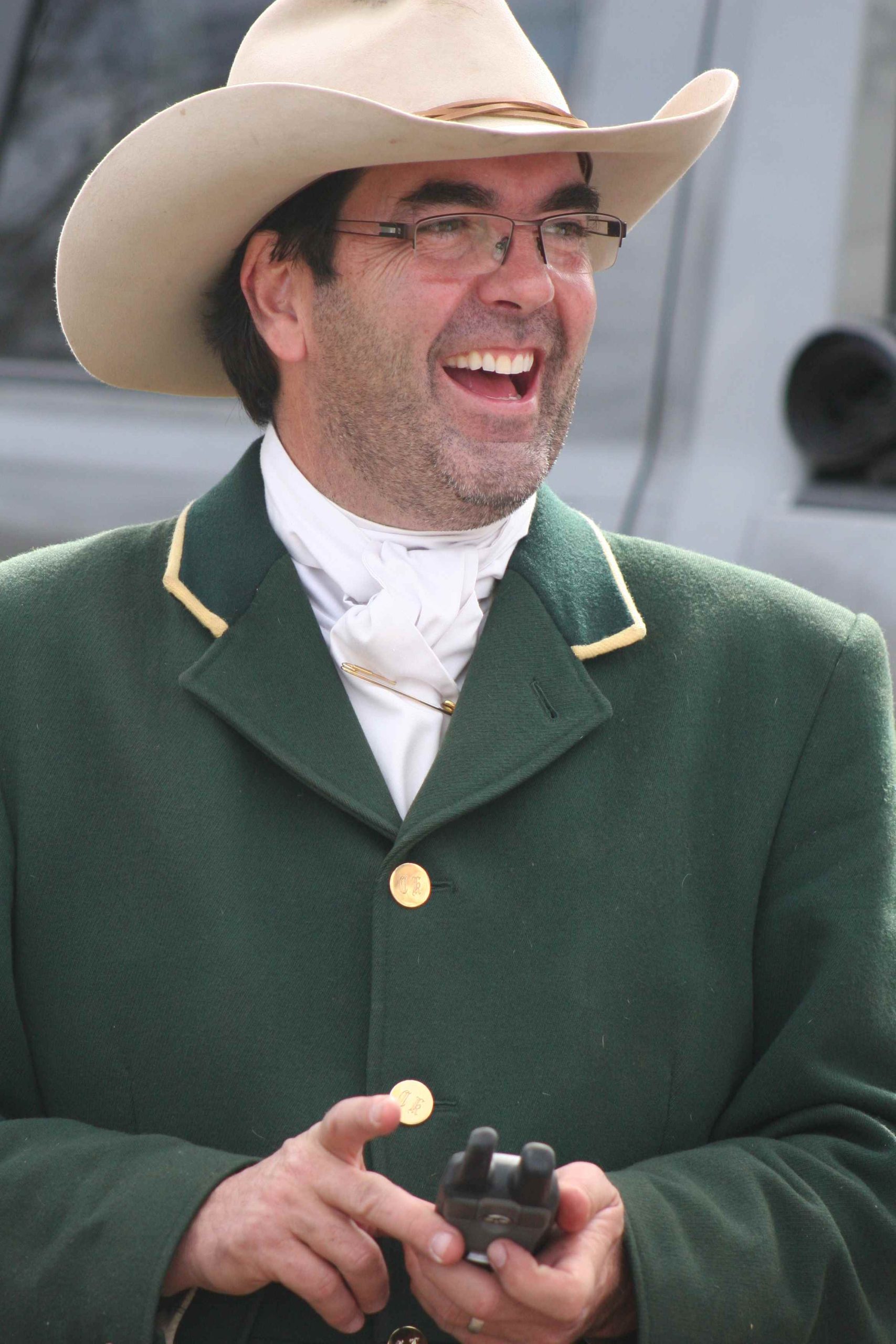smiling man with cowboy hat in green hunt coat
